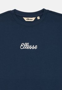 T-shirt in cotone blu navy con colletto a giro e logo "Ellesse" ricamato sul davanti. Tessuto morbido con un design semplice.