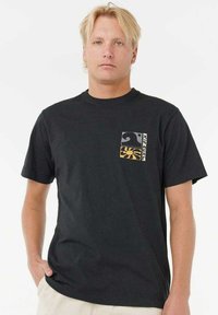 Schwarzes Baumwoll-T-Shirt mit einer Brusttasche, die aus zwei Farbblock-Designs besteht, darunter ein Wellen- und ein Sonnenstrahlenmuster. Kurze Ärmel, Rundhalsausschnitt.