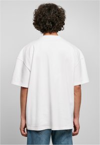 T-shirt bianco oversize in cotone con maniche corte, scollatura rotonda e vestibilità rilassata. Retro semplice senza grafiche o decorazioni.