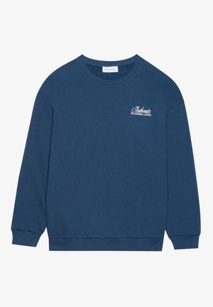 Sinine pusakariga, millel on pikad varrukad, soonikmustriga mansetid ja ümar kaelus. Rinnaosas on broderi tekst "Autentne NYC Pesapalli Liiga".