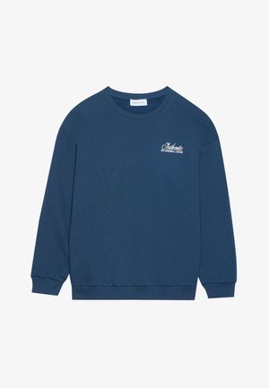 Sinine pusakariga, millel on pikad varrukad, soonikmustriga mansetid ja ümar kaelus. Rinnaosas on broderi tekst "Autentne NYC Pesapalli Liiga".