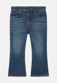 Jean en denim bleu foncé avec une coupe évasée, présentant des coutures orange contrastantes, des poches et un bouton de fermeture. Texture lisse avec une finition délavée.