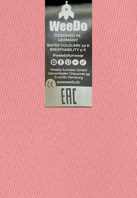 Rosa ribbad tyg med en svart etikett som visar text. Etiketten anger "WeeDo," designad i Tyskland, med vattenpelare och andningsförmåga betyg.