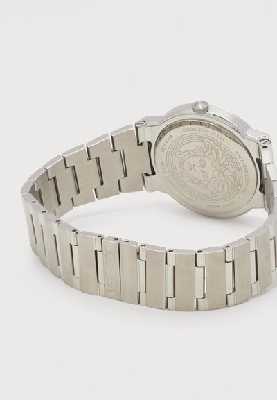 Ασημένιο ρολόι χειρός από ανοξείδωτο ατσάλι με συνδεδεμένο μπρασελέ, χαραγμένο λογότυπο κεφαλής Μέδουσας και επιγραφές στην πίσω θήκη.