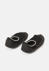 Pantofole grigie in feltro con una texture morbida, design a profilo basso e aperture elastiche. Suole piatte con una leggera curvatura sulla punta.