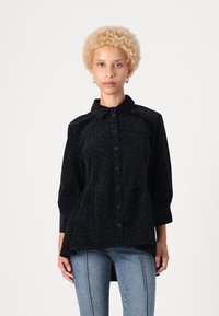 Svart leopardmønstret skjorte med krage, knappestolpe foran og trekvart lange ermer. Myk tekstur og peplum-design, brukt over blå jeans.