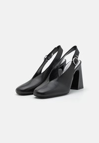 Czarne skórzane buty typu slingback z kwadratowym noskiem, wysokim blokowym obcasem i okrąłym srebrnym detalem na pasku wokół kostki.