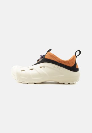 Weißer Slipper mit orangefarbenem Mesh-Kragen, schwarzem Besatz, Lüftungslöchern und elastischem Knebelverschluss, seitlich auf weißem Hintergrund betrachtet.