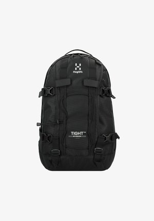 Sac à dos noir avec une surface en tissu texturé, des bretelles ajustables, des boucles latérales et un détail de logo. Il dispose d'un compartiment central et de poches externes.