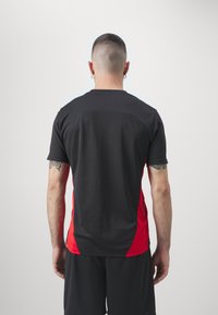 Black and red sports t-shirt with a round neckline, short sleeves, and a fitted design, featuring a smooth texture and contrasting color panels.