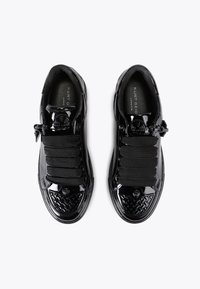 Un paio di sneakers in pelle sintetica nera con lacci neri larghi e punte texturate, marchiate "Kurt Geiger London" all'interno.