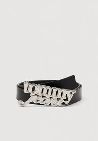 Μαύρη δερμάτινη ζώνη με αγκράφα λογότυπου "Tommy Jeans" σε ασημί χρώμα, που παρουσιάζει γυαλιστερή φινίρισμα και καμπύλο σχεδιασμό κειμένου.