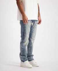 Lichtblauwe denim jeans met een slim fit, voorzien van versleten details en vervaging, gecombineerd met witte sneakers en een eenvoudig wit T-shirt.