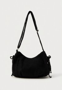 Borsa a tracolla in velluto a coste nero con forma curva, tracolla regolabile e dettagli con coulisse per la chiusura. Texture morbida e design minimalista.