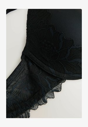 Schwarzer Spitzen-BH mit floralen Mustern, glatten Cups, verstellbaren Trägern und gewellten Kanten, die die filigrane Textur und das Design betonen.