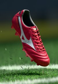 Gheat de fotbal roșu cu o finisare din piele netedă, având un accent argintiu, interior negru și cui cu cauciuc ridicat pentru aderență.