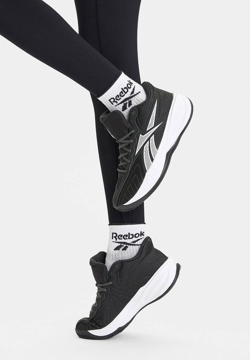 Mustad sportkingad valgete aksentide ja võrkmustriga, valgete Reeboki sokkidega, millel on must logo, kantud mustade retuusidega.