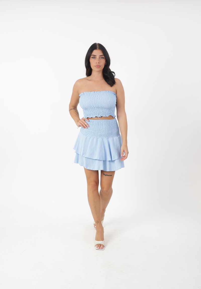 Set azzurro chiaro composto da due pezzi, caratterizzato da un top a fascia arricciato e una mini gonna a più strati con bordi arricciati. Tessuto liscio e textured.