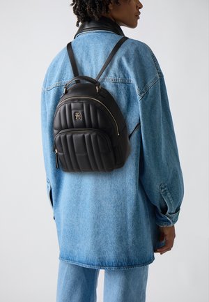 Schwarzer Kunstleder-Rucksack mit gestepptem Design, doppelten verstellbaren Tragegurten, goldenen Hardware-Akzenten und einem Vorderfach mit Reißverschluss.