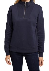 Mörkblå sweatshirt med hög krage, halvmåttsdragkedja och en texturerad, fyrkantig panel på framsidan. Ribbstickade muddar och nederkant. Mjukt material.