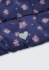 Marineblauwe stof met bloemenpatronen in roze en groen; heeft een lichtgrijze hartaccent. Zachte textuur met een gewatteerd ontwerp.