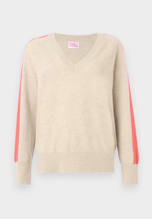 Bézs V-nyakú pulóver hosszú ujjal, melyen élénk rózsaszín csík fut a válltól a mandzsettáig.