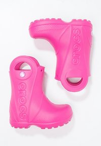 Bottes imperméables roses avec une finition brillante, dotées d'un bout arrondi, de poignées découpées et de semelles à texture antidérapante pour une meilleure adhérence.