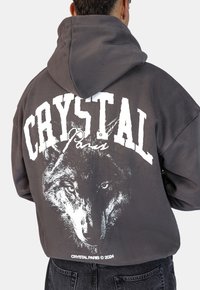Felpa grigia con una grande grafica di un lupo bianco e il testo "CRYSTAL Paris" sul retro, caratterizzata da una vestibilità comoda e una morbida trama del tessuto.