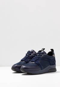 Mörkblå sneakers i läder och mocka, med en strukturerad detalj, snörning och en vadderad sula för komfort.