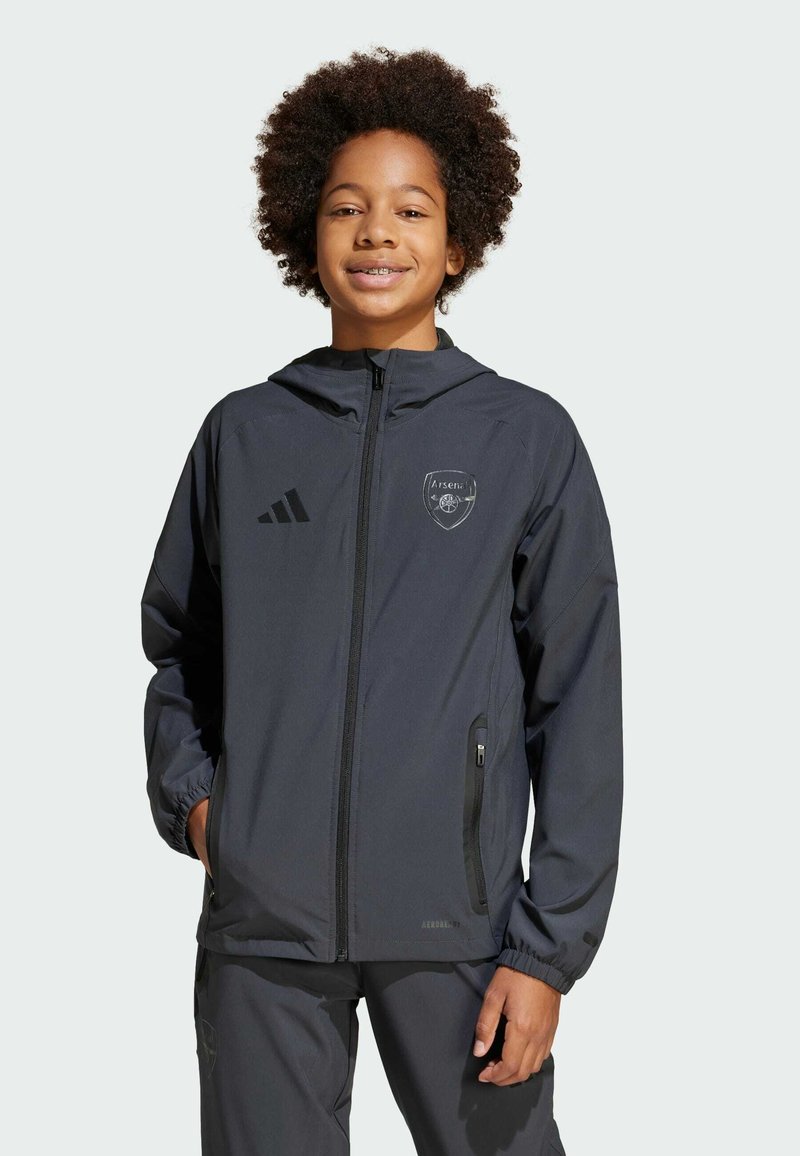 Veste de sport noire avec capuche, fermeture éclair et deux poches latérales. Comprend un logo d'Arsenal et trois bandes sur la poitrine gauche.