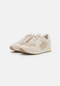 Baskets beige clair avec un motif texturé, fabriquées avec un mélange de matériaux, fermeture à lacets et zip sur le côté. Accentuées de détails métalliques.