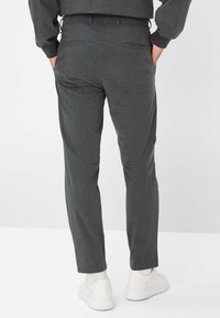 Donkergrijze op maat gemaakte broek van een textuurstof, met achterzakken en een slim fit. Gepaard met witte lage sneakers.