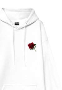 Felpa bianca con cappuccio caratterizzata da una rosa ricamata rossa con foglie verdi e il testo "propaganda" sotto il fiore. Lacci sul cappuccio.