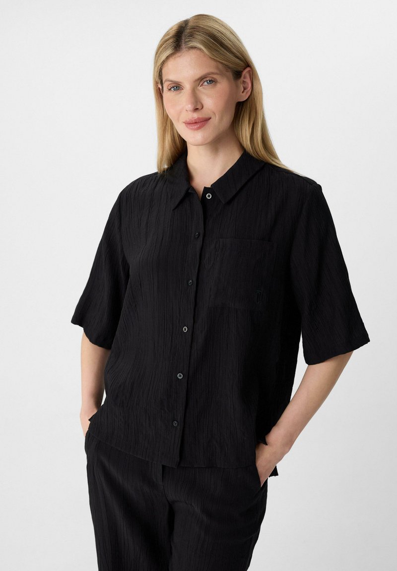Zwarte korte-mouwen shirt van een textuurstof, met een knoopsluiting aan de voorkant, een enkele borstzak en een relaxte pasvorm, gecombineerd met bijpassende broek.