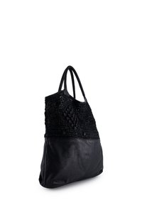 Černá taška typu tote s tkaným horním dílem a hladkým koženým spodkem. Má dlouhá ucha a texturované vzory na tkané části.