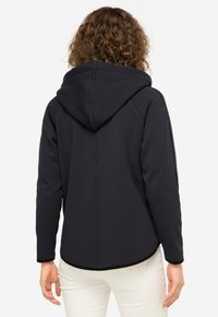 Felpa con cappuccio di un blu navy scuro, con una texture liscia, caratterizzata da un orlo curvo e finiture a contrasto lungo i polsini e l'orlo. Vista posteriore mostrata.
