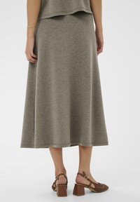 Pelēks džersija maksi svārki ar brīvu piegriezumu, kas izceļas ar gludu struktūru. Saskaņoti ar brūnām austu augstpapēžu sandālēm ar kvadrātveida papēžiem.