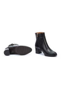 Bottines en cuir noir avec un bout rond et un talon block de hauteur moyenne. Présente une fermeture éclair sur le côté et une semelle extérieure en caoutchouc texturé.