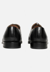Schwarze Lederschuhe mit glatter Oberfläche, ausgestattet mit einem strukturierten Design an den Seiten und einer stabilen schwarzen Sohle. Klassische, abgerundete Form.