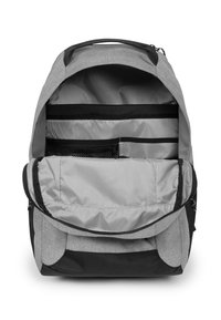 Mochila gris con una base negra, que cuenta con múltiples compartimentos, bolsillos de malla y con cremallera, y un suave revestimiento interior.