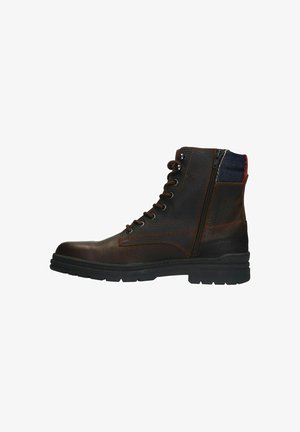 Bottine en cuir marron avec un design à lacets, fermeture éclair sur le côté, accent en tissu bleu et rouge au niveau du col, et semelle en caoutchouc texturé.