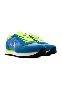 Sneakers in camoscio blu con lacci verde brillante, dotati di una suola intermedia bianca e una suola esterna in gomma nera. Il design include il logo sul lato.