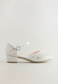 Błyszczący, srebrny but na kostkę z zaokrąglonym noskiem, niskim niskim obcasem i dekoracyjną klamerką. Miękka różowa podszewka wewnątrz.