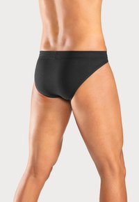Schwarze Herrenunterhose aus weichem, glattem Stoff; verfügt über einen hochgeschnittenen Beinausschnitt, einen elastischen Bund und minimale Nähte für eine bequeme Passform.