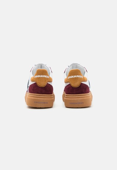 Las zapatillas multicolores cuentan con una parte superior de cuero blanco, detalles en ante burdeos, una pestaña en el talón de color marrón claro y una suela de goma texturizada con una marca.