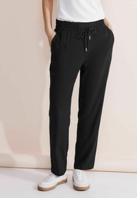 Zwarte, relaxte jogger pants met een elastische tailleband, trekkoordsluiting en zijzakken, gemaakt van een gladde stof.