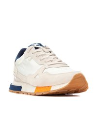 Zapatillas de ante beige y cuero blanco con una suela intermedia texturizada, acentos en azul marino y detalles en naranja en la suela exterior. Presenta un diseño con cordones.