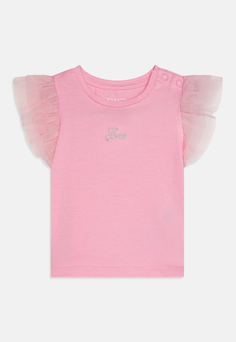 Rozā īsa piedurkne T-kreklā, izgatavots no mīksta kokvilnas. Ar caurspīdīgiem tilla volāniem uz piedurknēm un sudraba "Guess" logo priekšpusē.