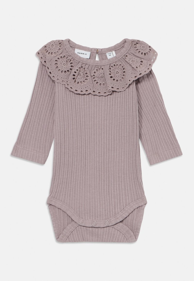 Body de manga larga con canalé en lavanda suave, con un cuello decorativo de volante con ojales y cierre a presión en la parte inferior. Material de algodón suave.