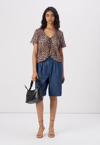 Leopard-print short-sleeve blouse, denim shorts, strappy sandals, and a small black handbag with textured detailing.